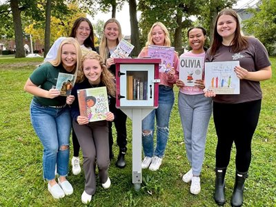 A group of people standing outdoors holding books